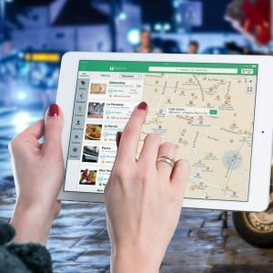 Hands using a digital map on a tablet in an urban setting at night, illustrating navigation and technology.